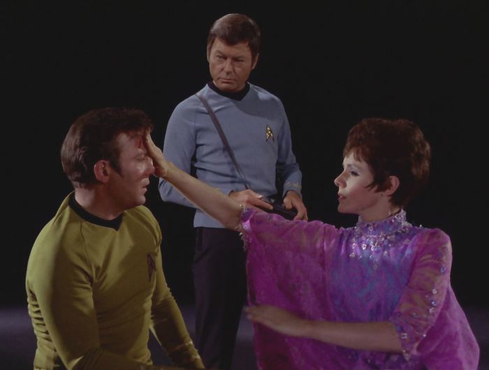 Gem is helping the injured Kirk as McCoy looks on